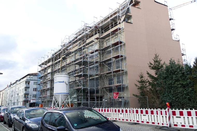 Wohnhaus mit Gerüst während der Fassadenarbeiten, Dämmung teilweise aufgebracht